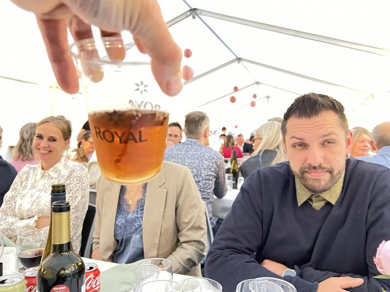 Stor fest i hvidt festtelt – en gæst hæver et krus Royal fadøl